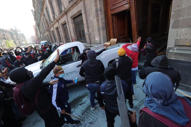 Jóvenes de Ayotzinapa derriban una puerta del Palacio Nacional